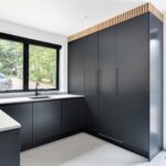 Charcoal handleless utility room with full-height storage, a slatted oak detail above and an L-shaped worktop beneath the window